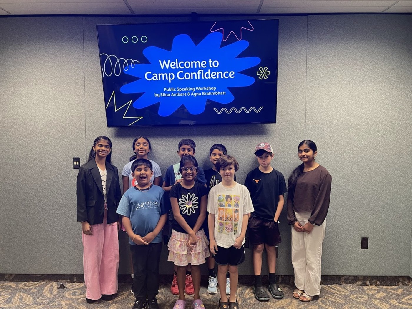 Camp Confidence students standing together in front of a welcome screen after the first workshop